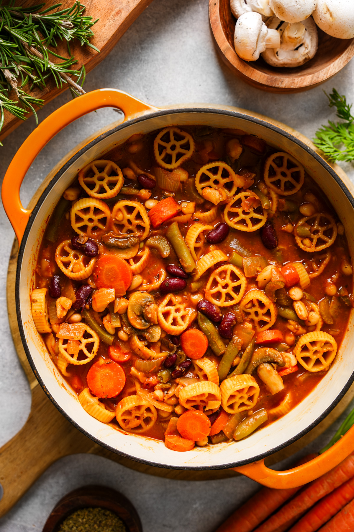 a pot of the hearty minestrone soup  surrounded by the fresh herbs