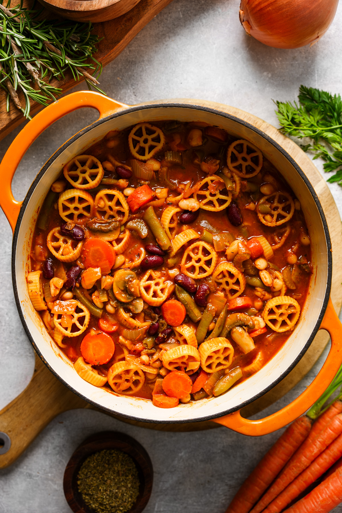 the pot of minestrone soup with fresh ingredients all around it
