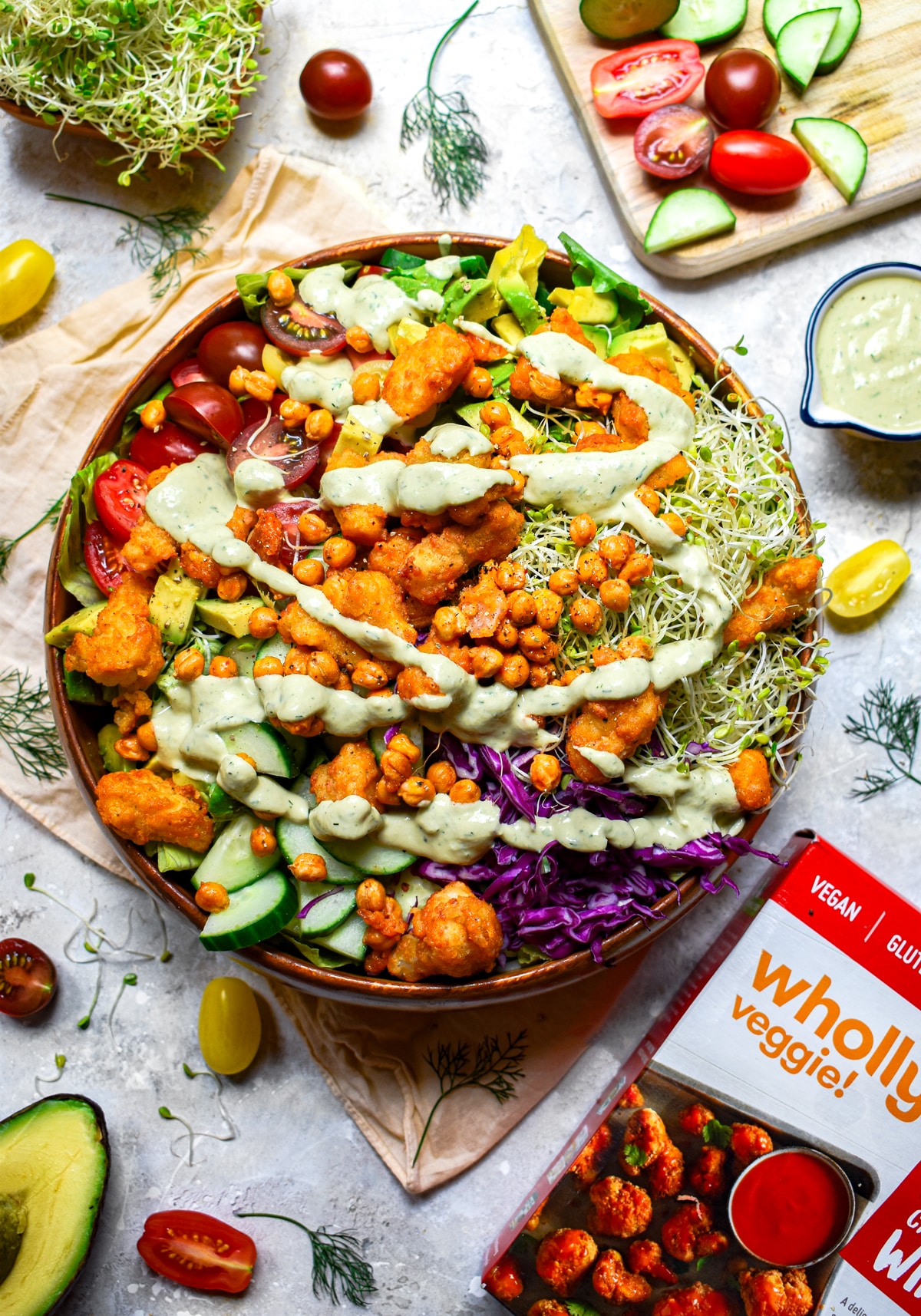 Vegan buffalo cauliflower salad with crispy chickpeas, fresh vegetables, sprouts, and creamy dairy-free ranch dressing, served with Wholly Veggie buffalo cauliflower wings
