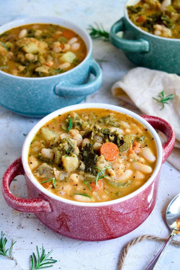 vegan kale and white bean soup with in bowls with fresh herbs on top