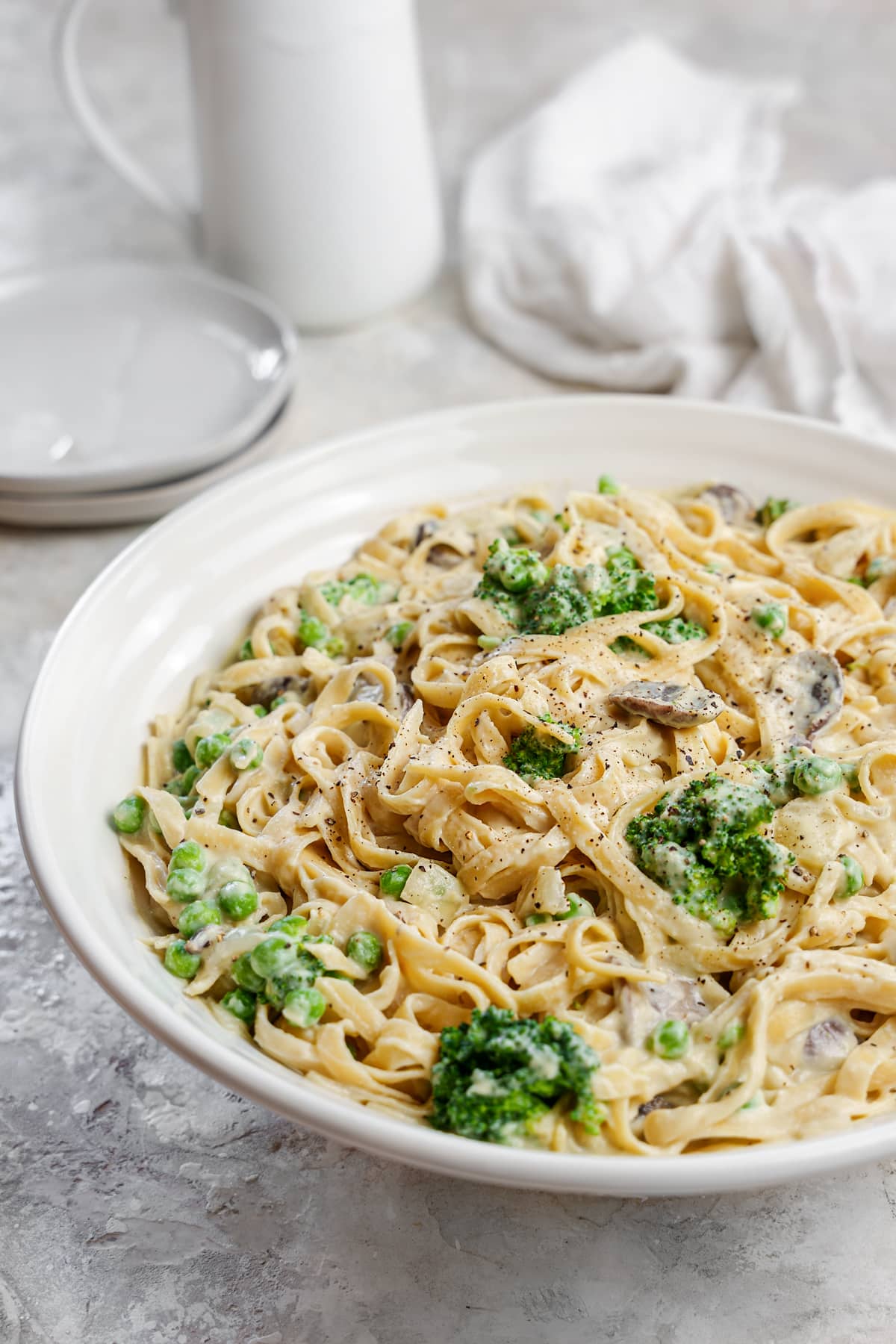 a large bowl of the fettuccine with cauliflower alfredo mixed with the cooked broccoli, mushrooms, peas, and onions