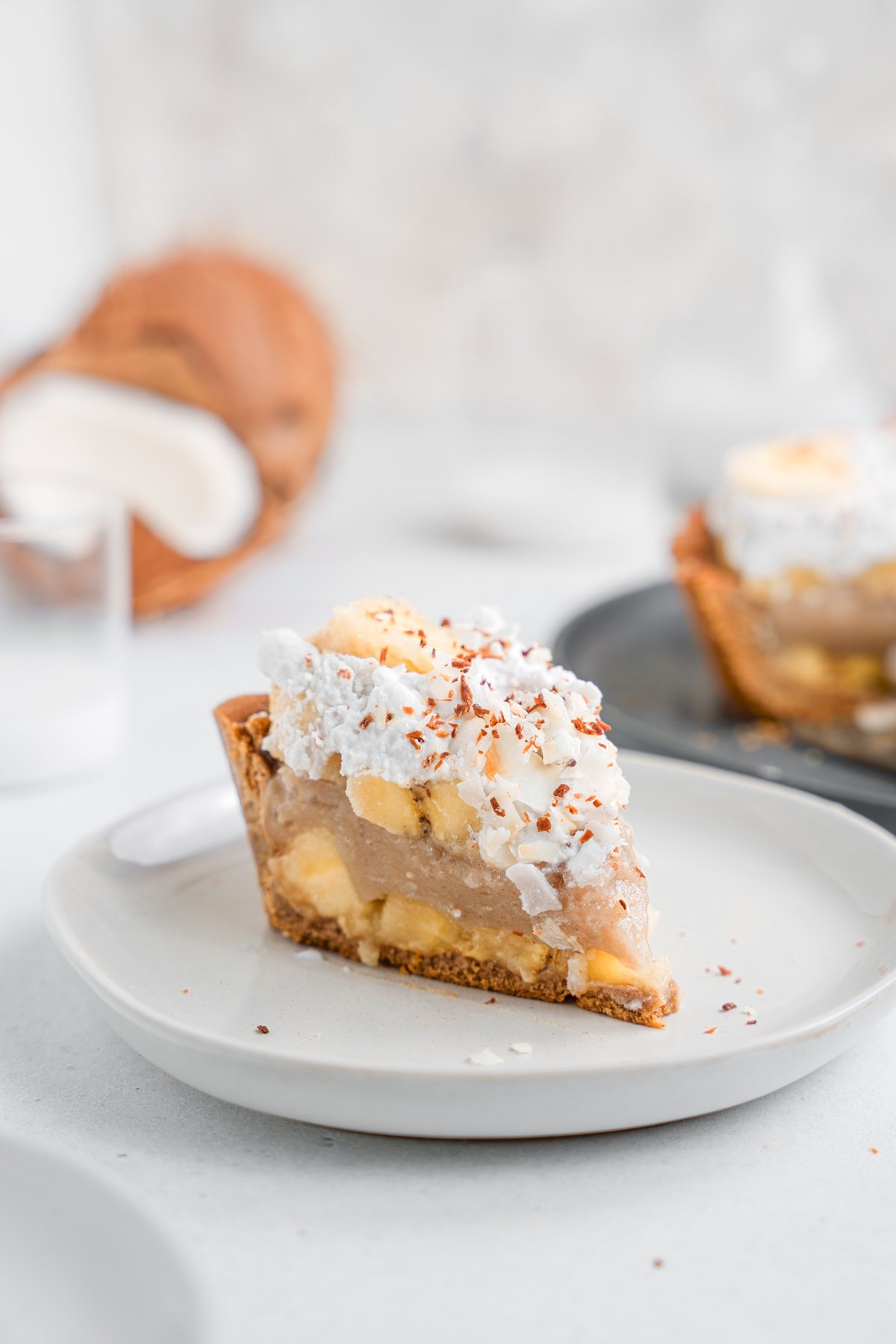 slice of the vegan banana cream pie recipe with coconut frosting and toasted coconut