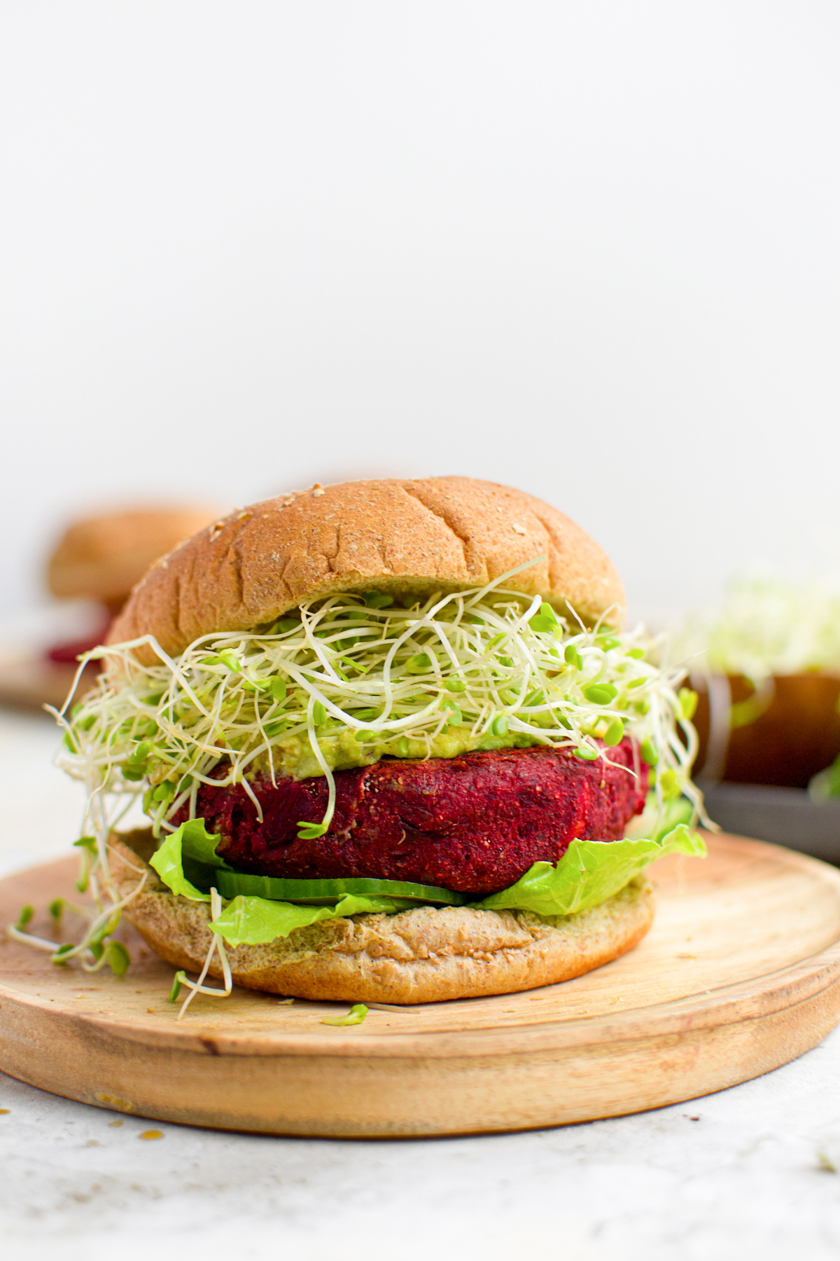 the sweet potato beet burger with sprouts and mashed avocado, and cucumbers on a gluten-free buns