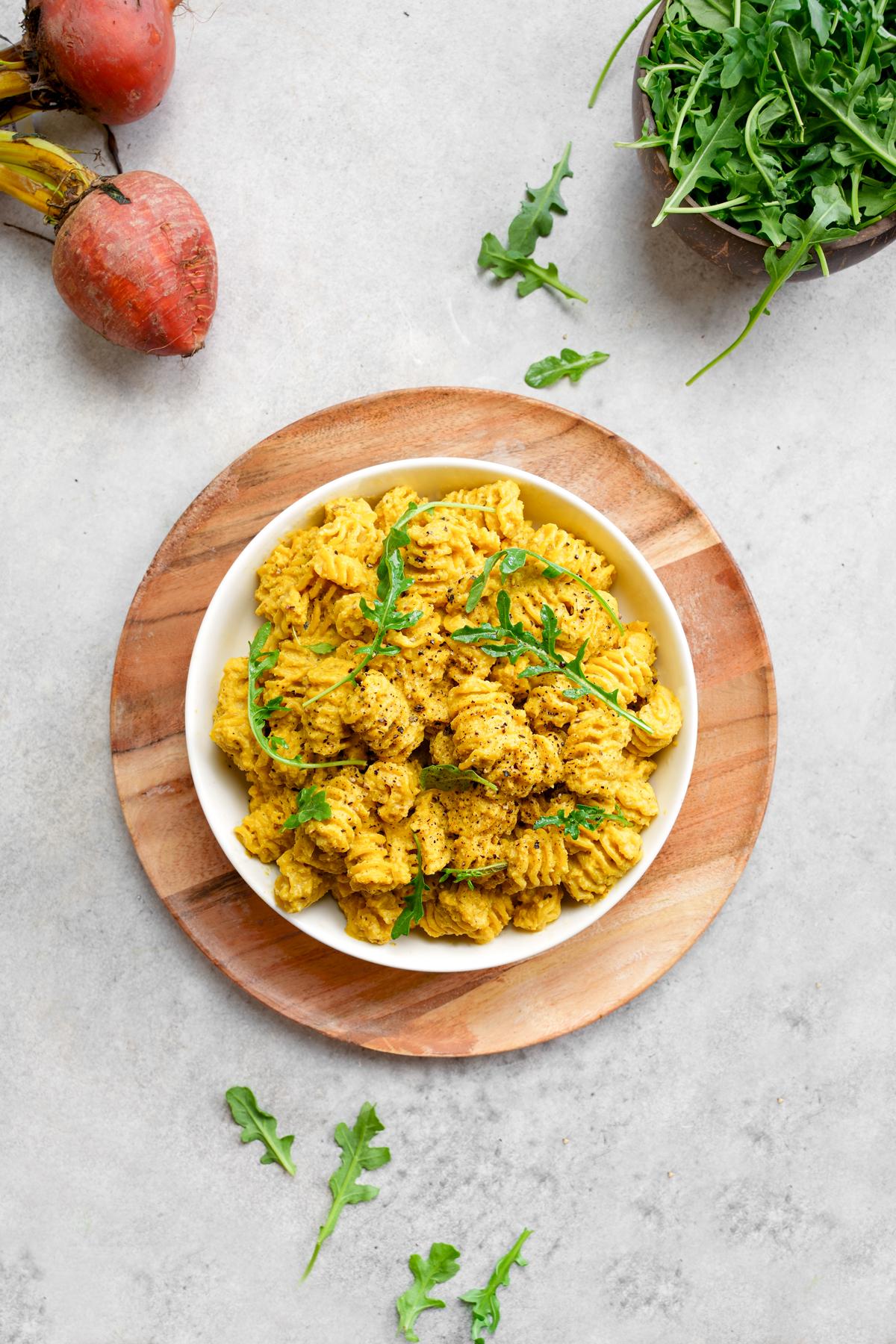 golden beet pasta in a pasta bowl topped with fresh arugula