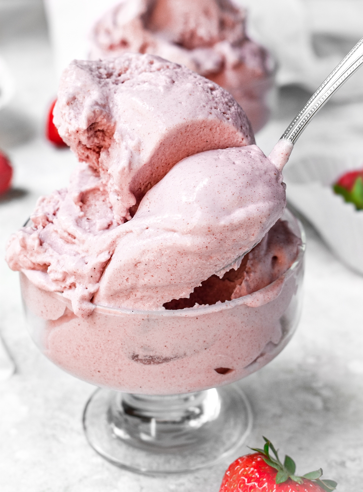 the creamy vegan strawberry ice cream with a scoop being taken out of it