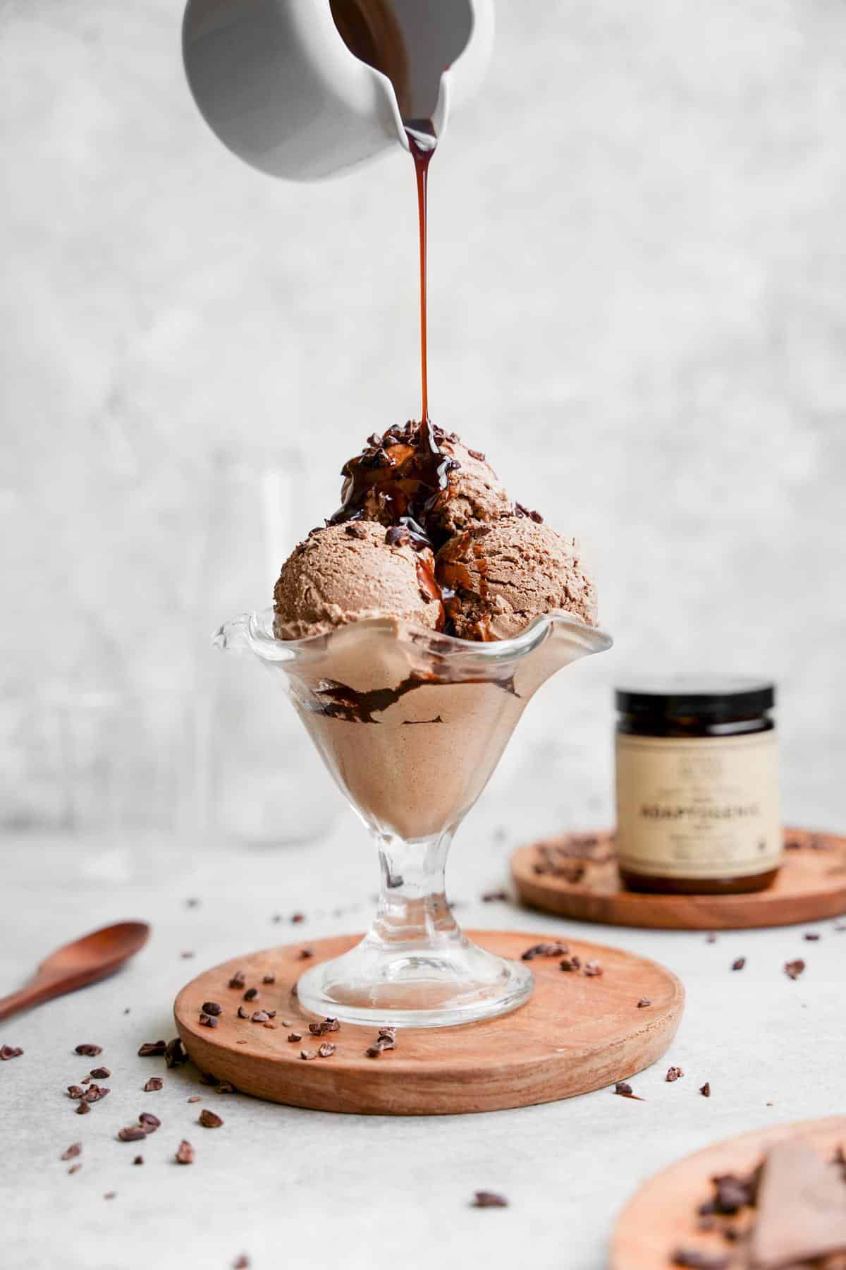 the mushroom ice cream in a bowl with chocolate sauce being poured on top of it