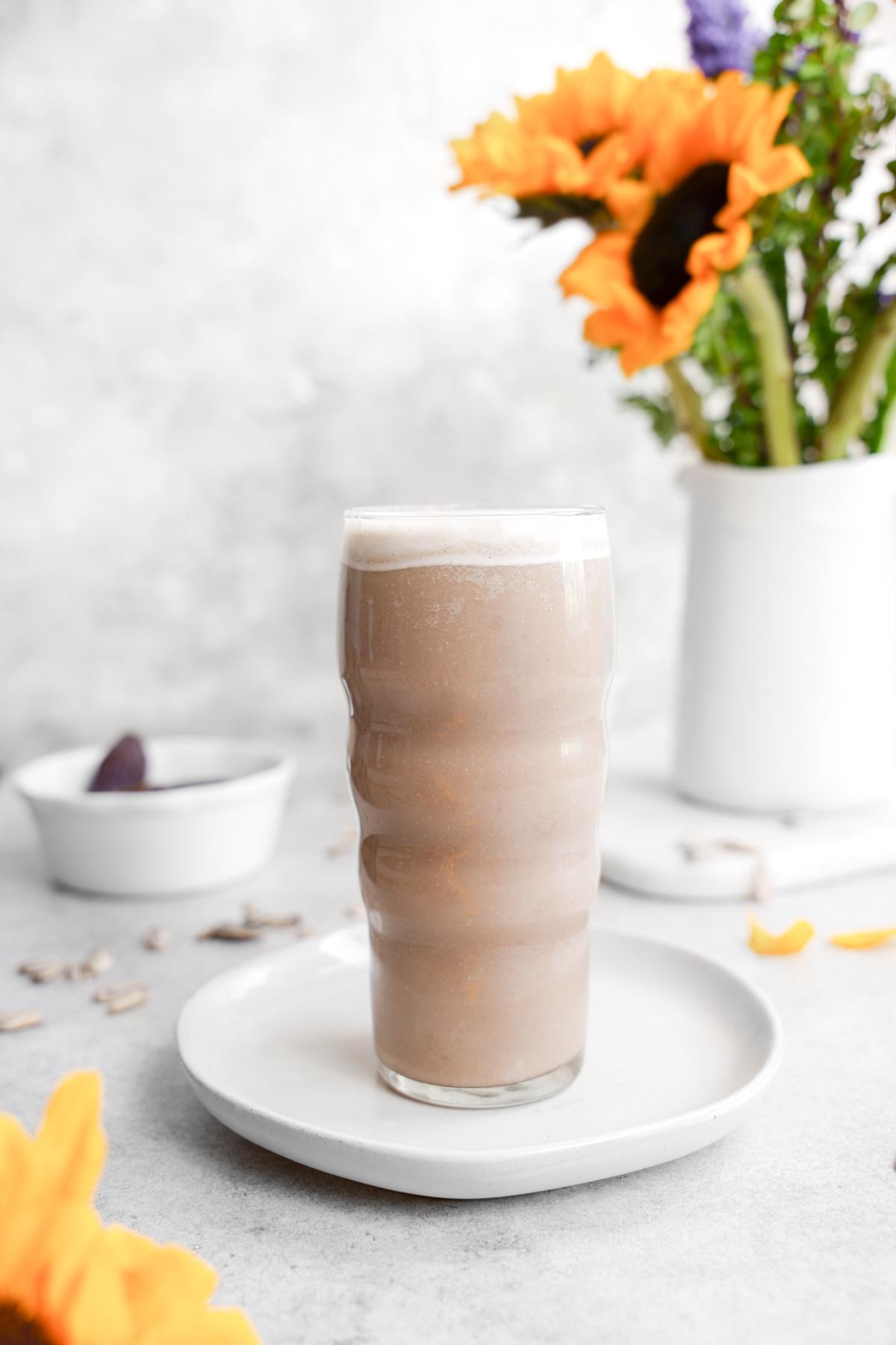 sunflower seed milk in a glass cup with fresh sunflowers in the background