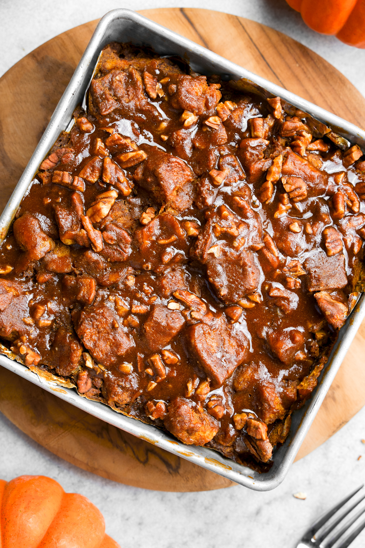 the vegan pumpkin bread pudding in a brownie pan with the caramel pecan glaze on top