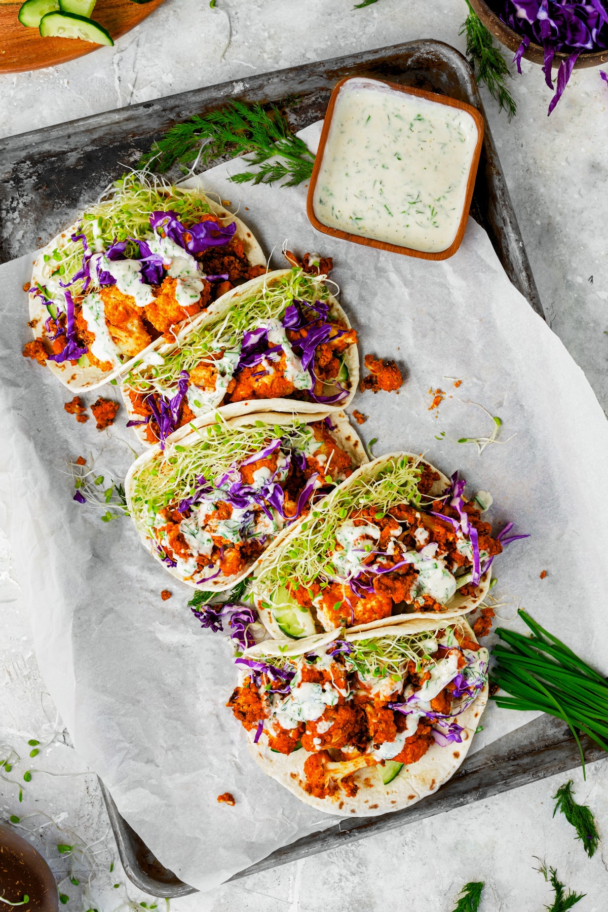 looking down at multiple buffalo cauliflower tacos lined up witth the vegan ranch next to it