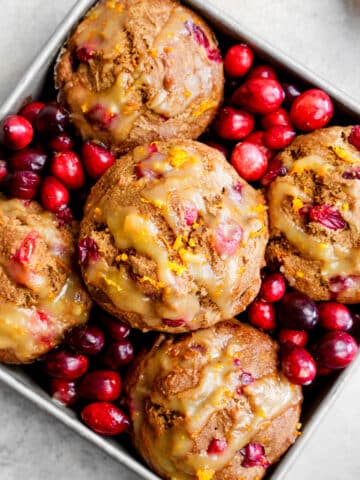 vegan cranberry orange muffins in a rustic container with fresh cranberries