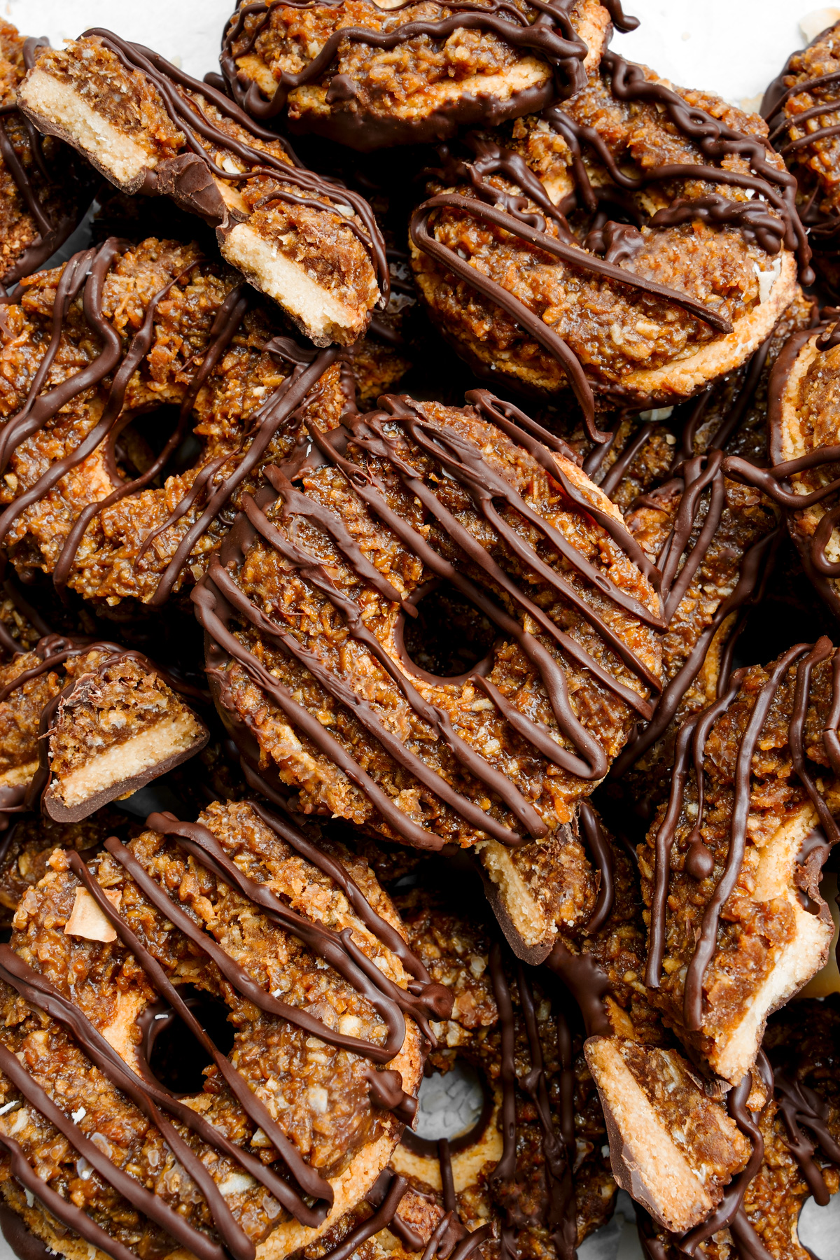 the gluten-free samoas stacked on top of each other, some broken in half to show the cookie layers