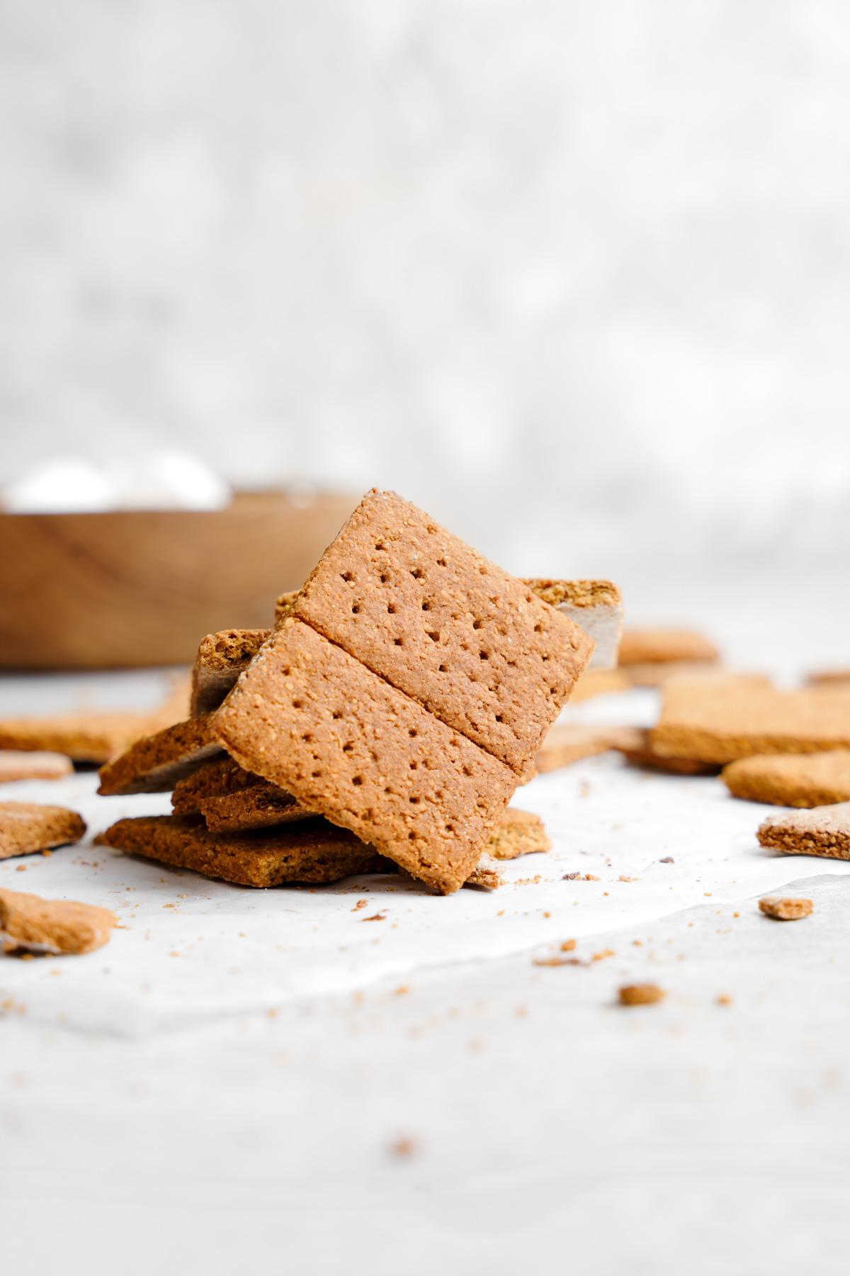 the vegan graham crackers stacked on top of each other with one standing up straight leaning against them