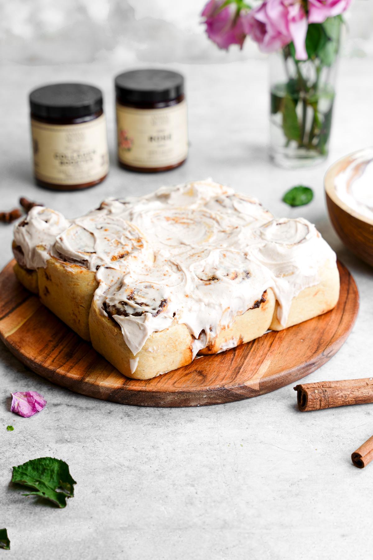 the chai cinnamon rolls all together on a plate with the cream cheese frosting lathered on top