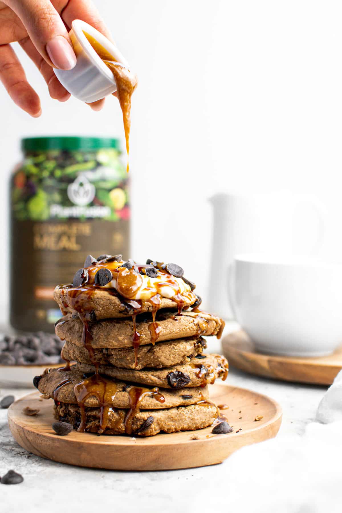 pouring the vegan caramel on top of the chocolate protein pancakes