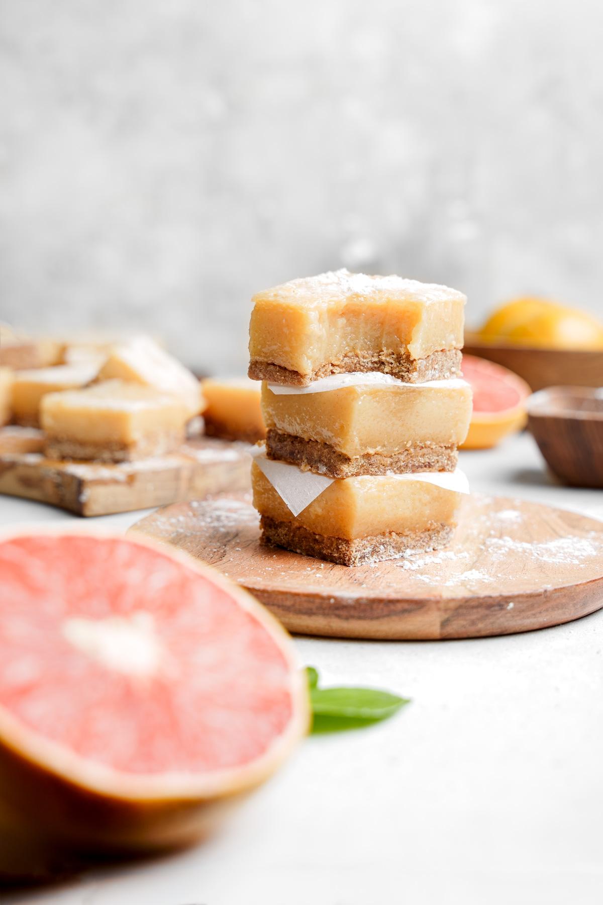 the grapefruit bars stacked on top of each other with a bite taken out of one