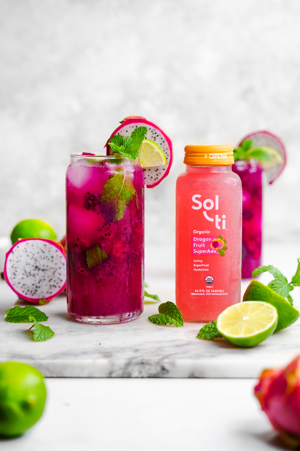the dragon fruit mocktail with the sol-ti drink next to it and fresh mint and dragon fruit around it