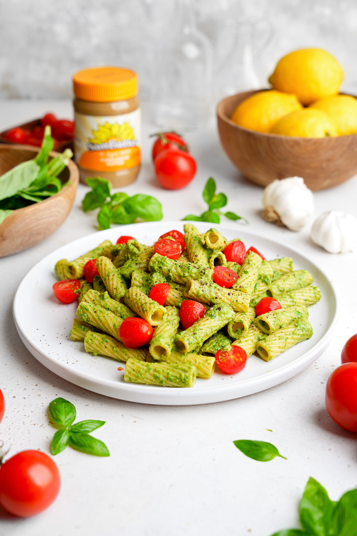 the nut free pesto pasta with the sunbutter container and a bowl of fresh lemons