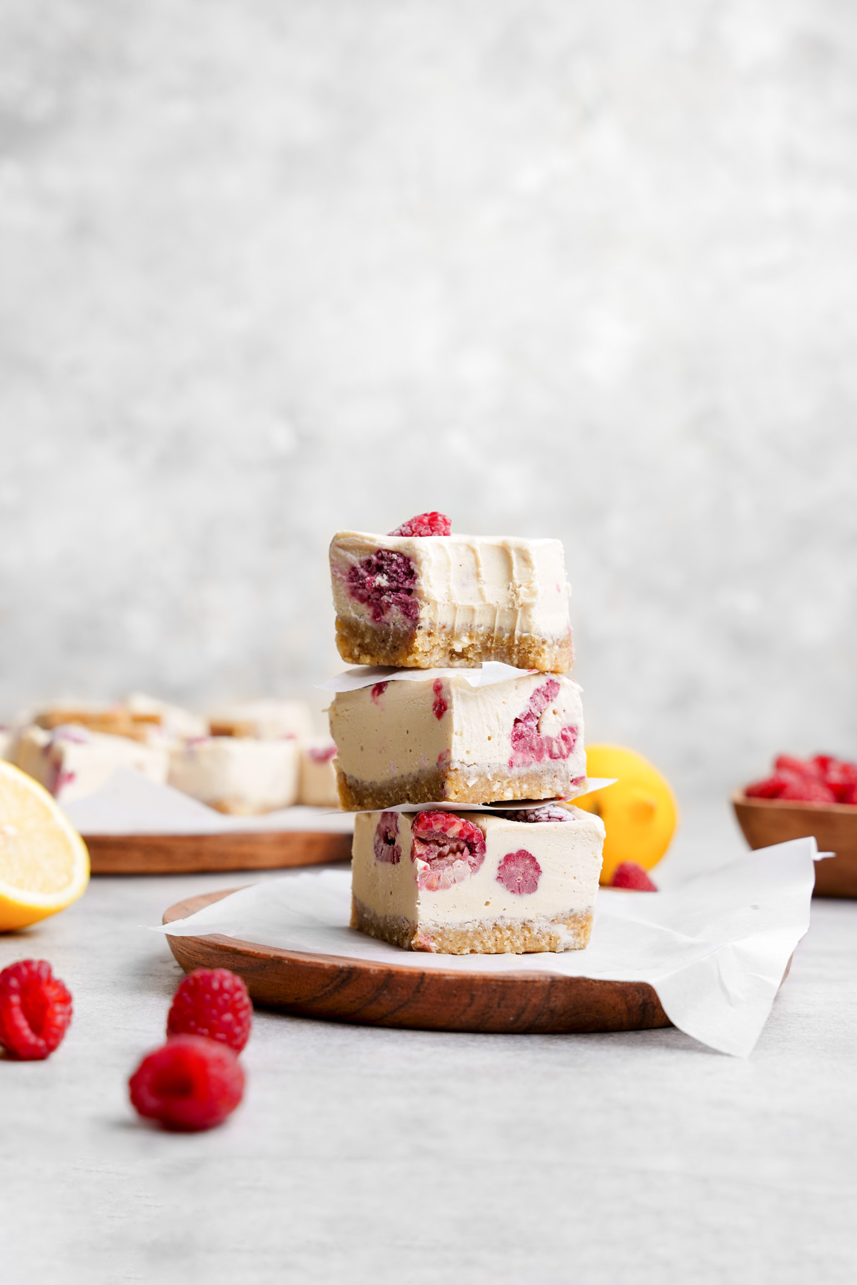 the raw vegan lemon bars stacked on top of each other with a bite taken out of the top one to show the smooth and creamy texture.