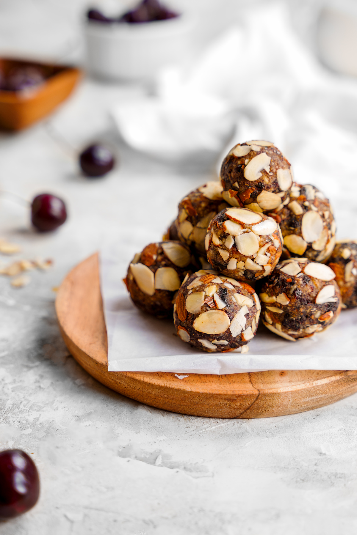 looking down at the cherry balls on a plate with fresh cherries and almonds all around