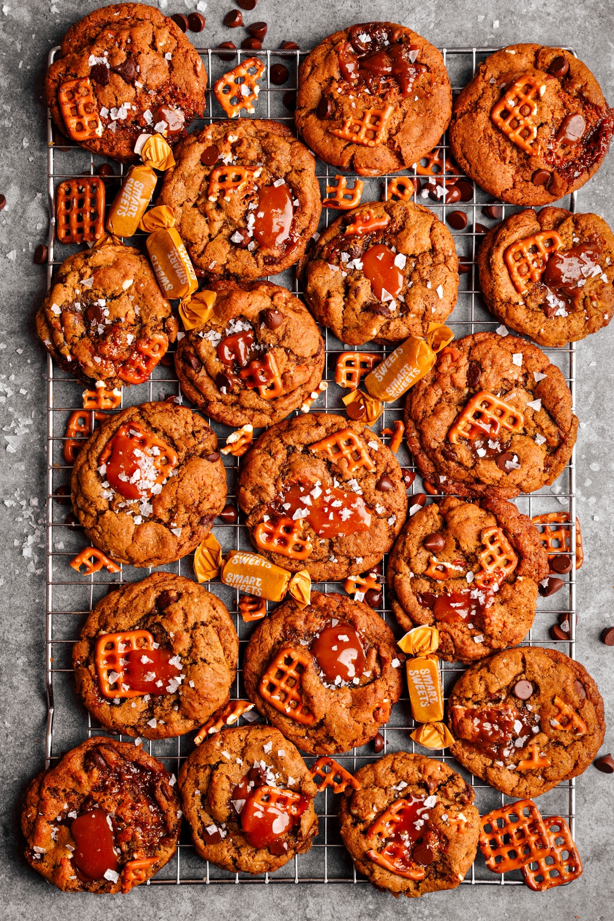 the vegan caramel pretzel cookies on a cooling rack with pretzel pieces and smart sweets caramels with them
