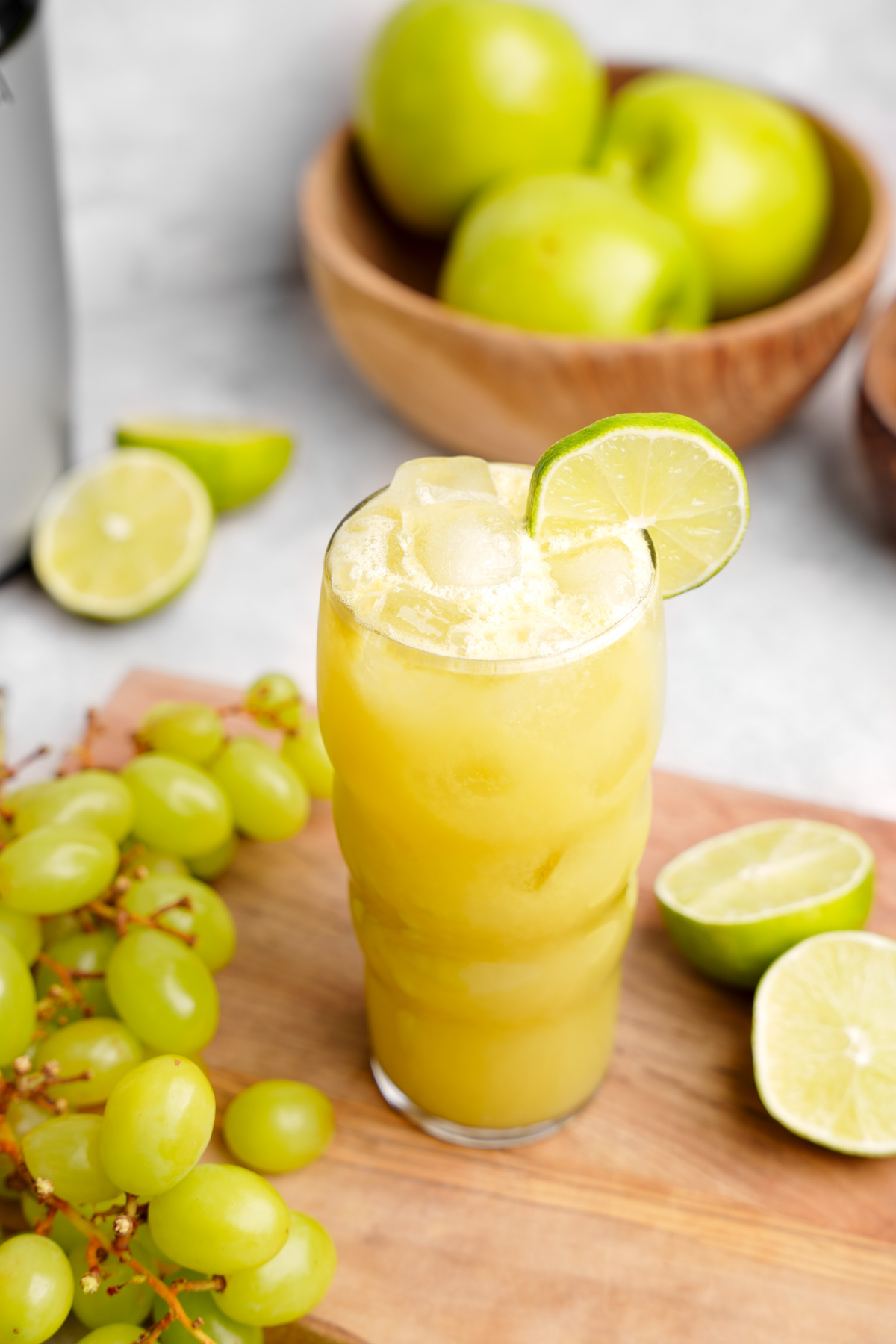looking down at the green grape juice with fresh grapes and limes around it