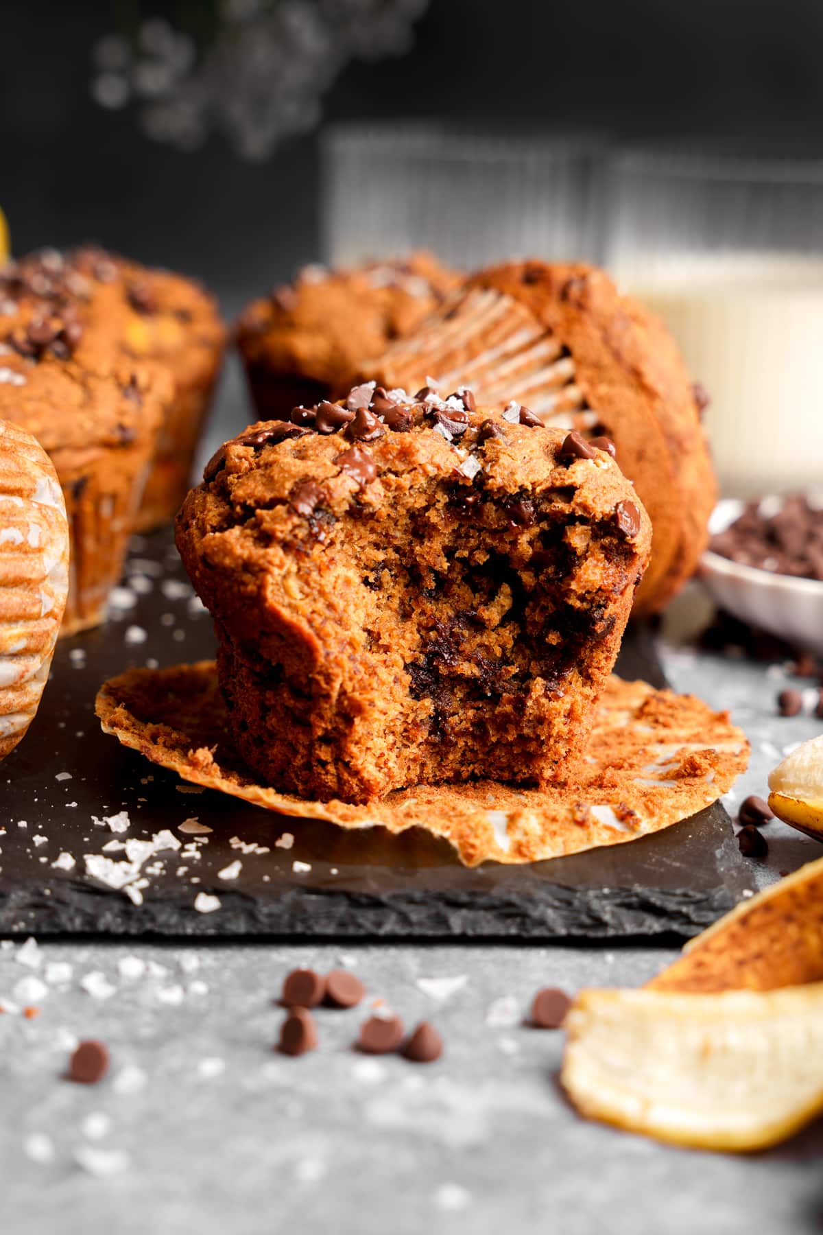 a close up of the chocolate chip banana muffins with a bite taken out of one to show the fluffy texture