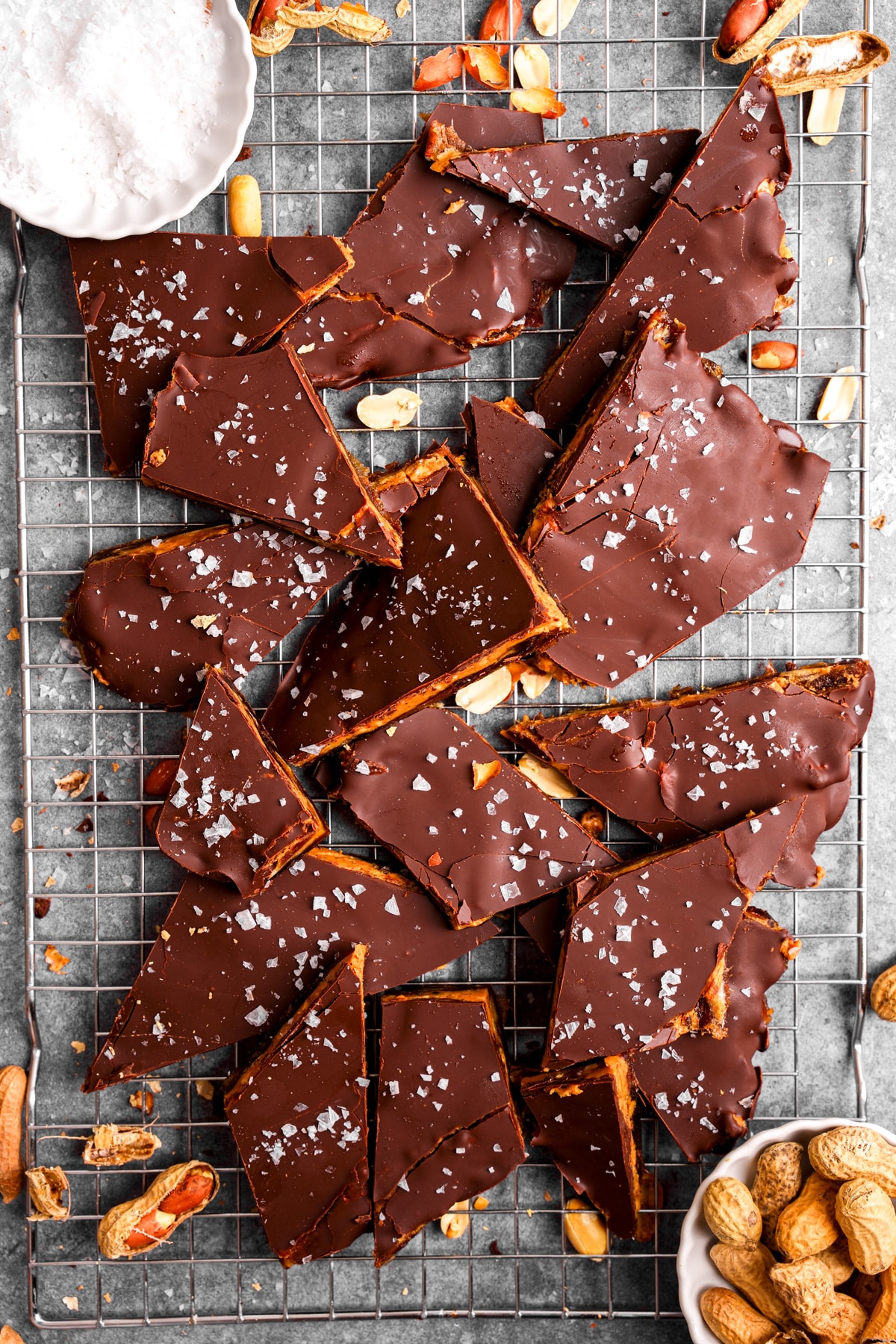 looking down at the broken pieces of date bark on a wire rack with peanuts and flaky salt around them