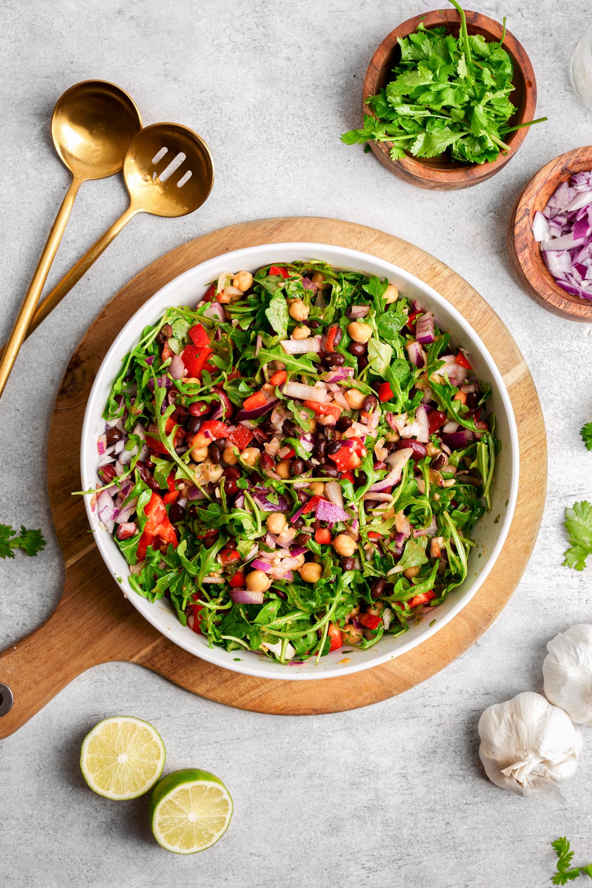 looking down at the vegan bean salad with fresh ingredients and serving spoons next to it