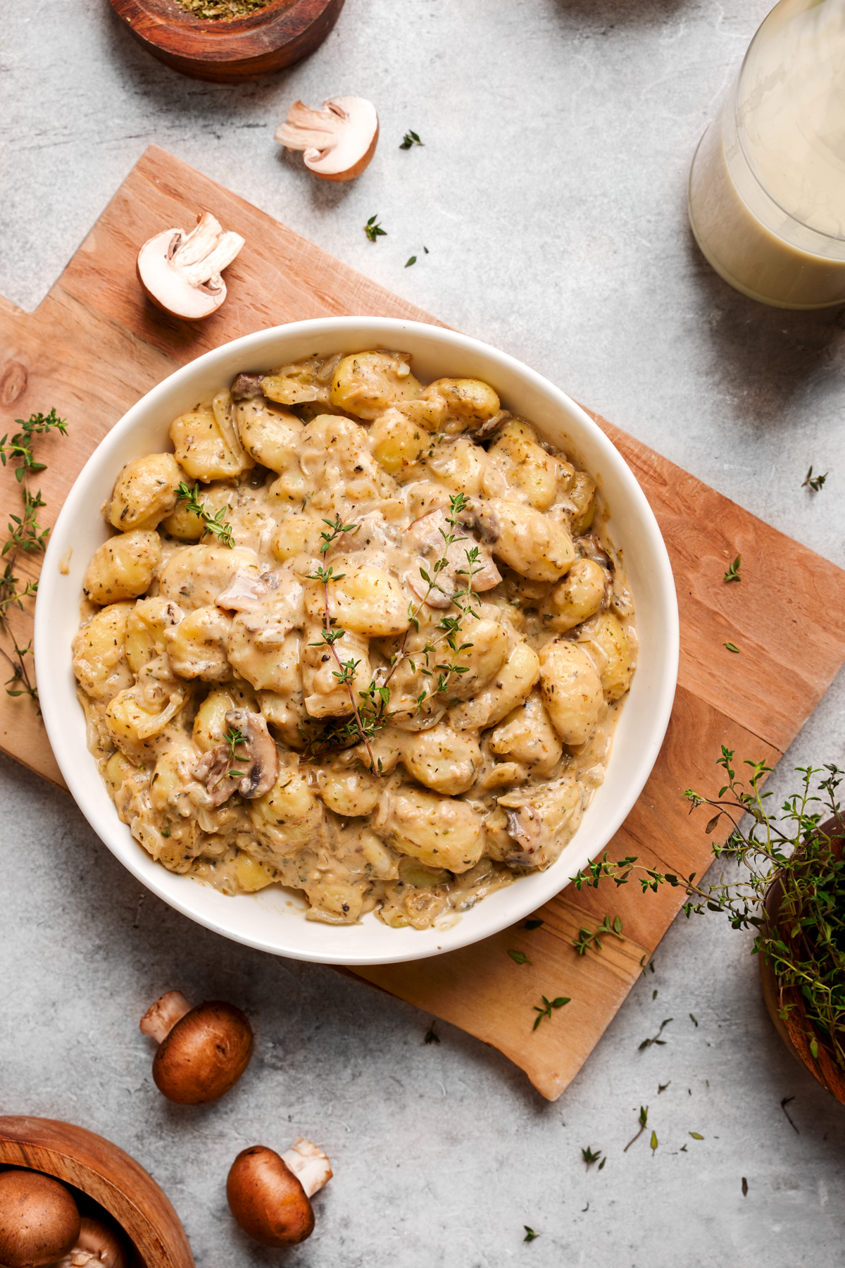 looking down at a bowl of the creamy vegan gnocchi with fresh herbs all around it