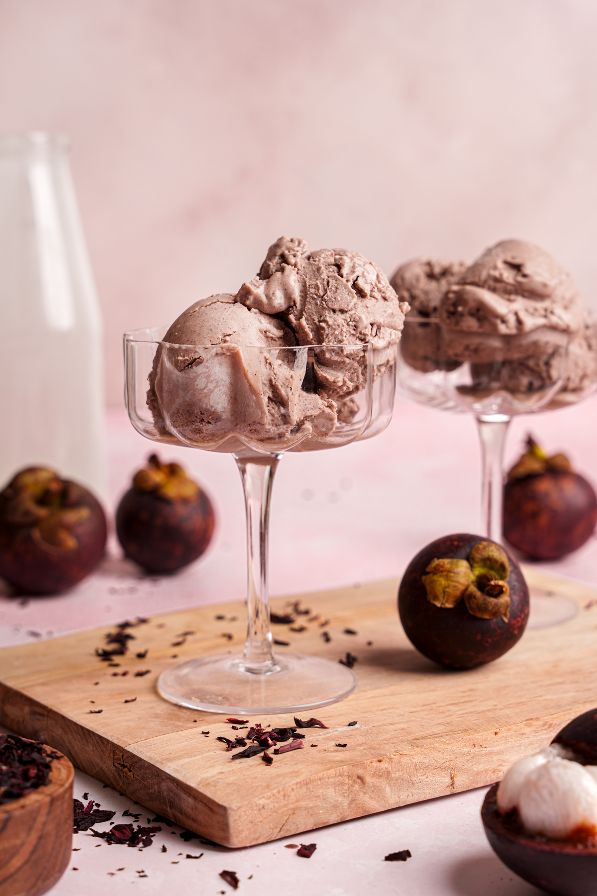 the mangosteen ice cream with fresh mangosteens and hibiscus leaves all around it