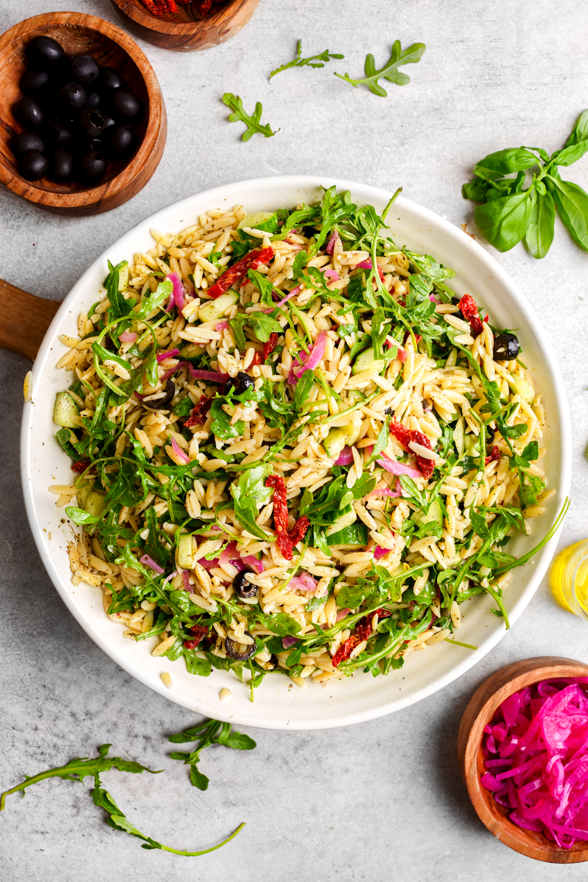 a bowl of the vegan orzo salad with the fresh ingredients all around