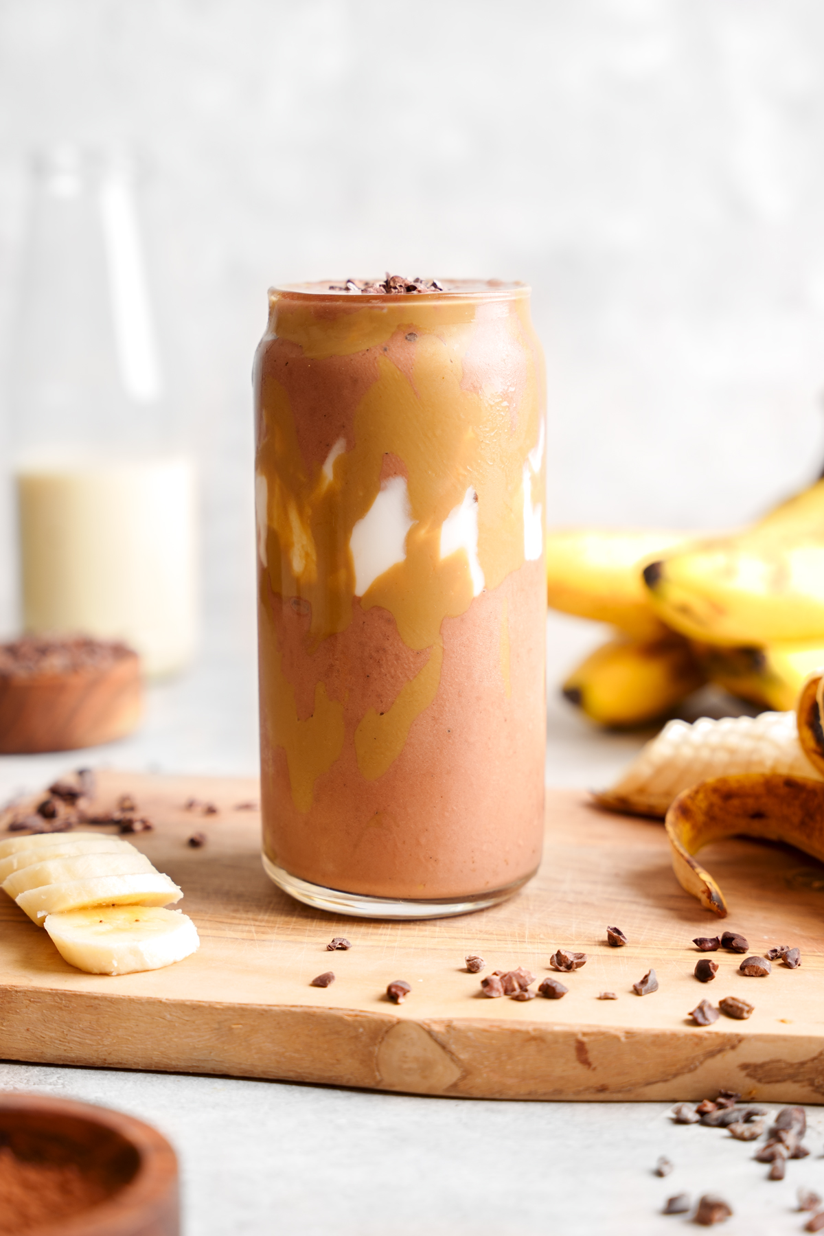 the chocolate banana smoothie with fresh bananas and cacao nibs all around it