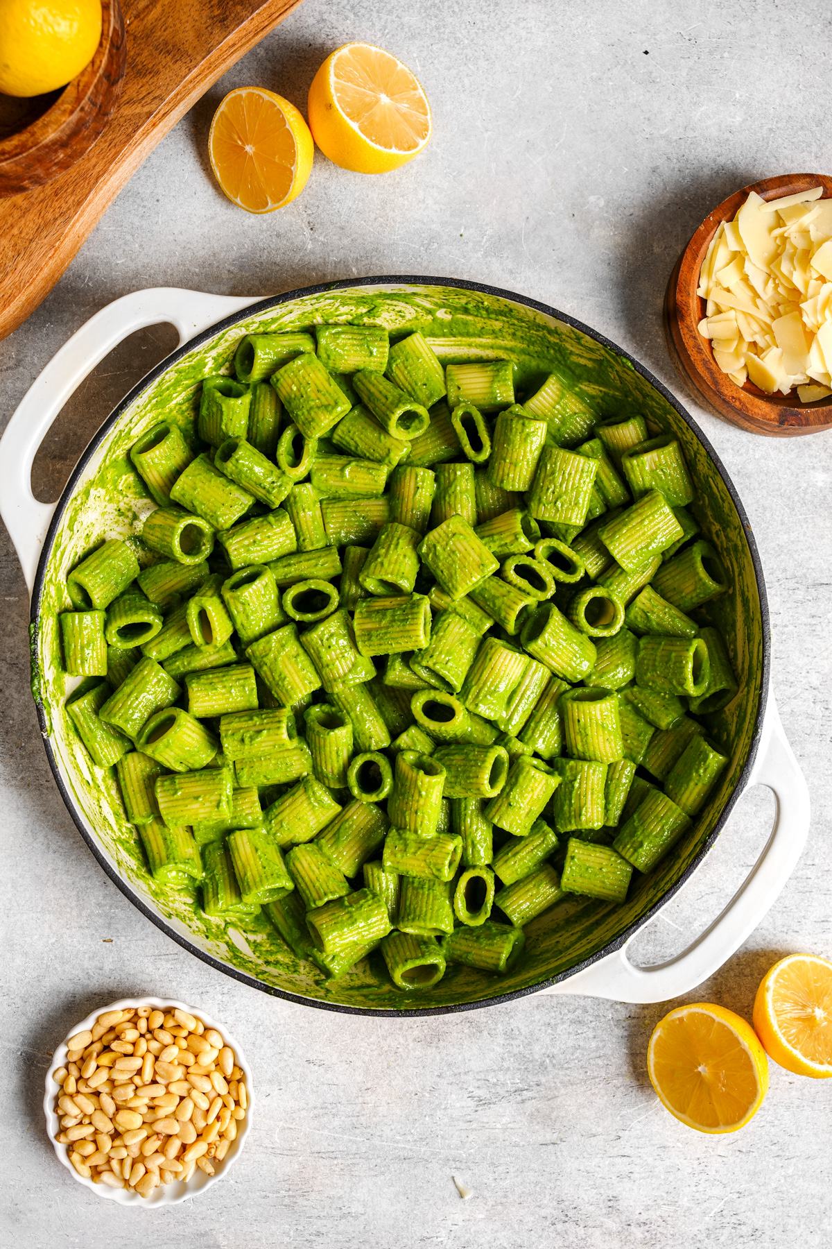 the spinach pesto pasta with pine nuts, parmesan, and lemons around it