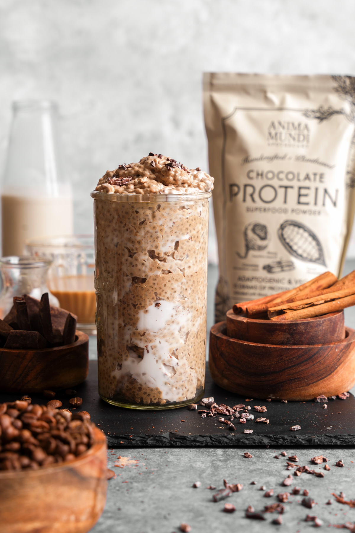 the coffee chia protein pudding with fresh ingredients around it next to the anima mundi protein powder