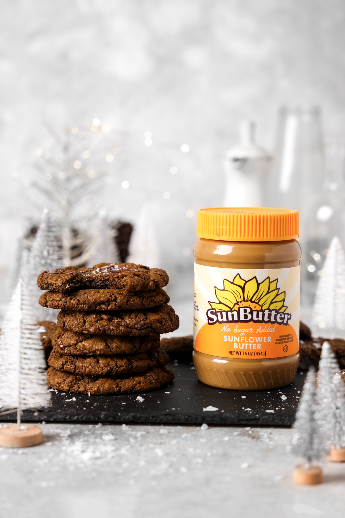 the double chocolate sunbutter cookies stacked on top of each other in a winter scene