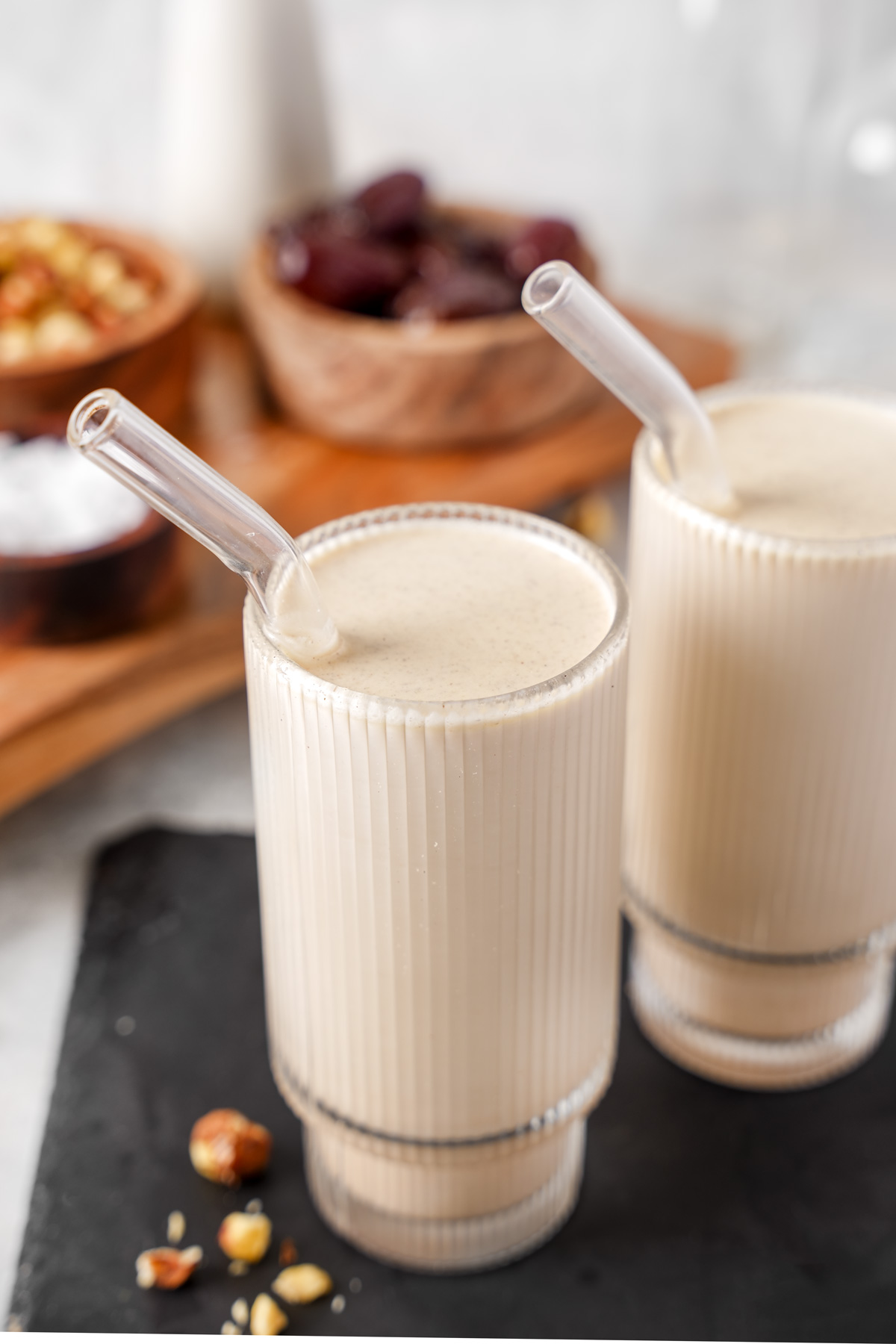 the hazelnut milk in glasses with hazelnuts next to it