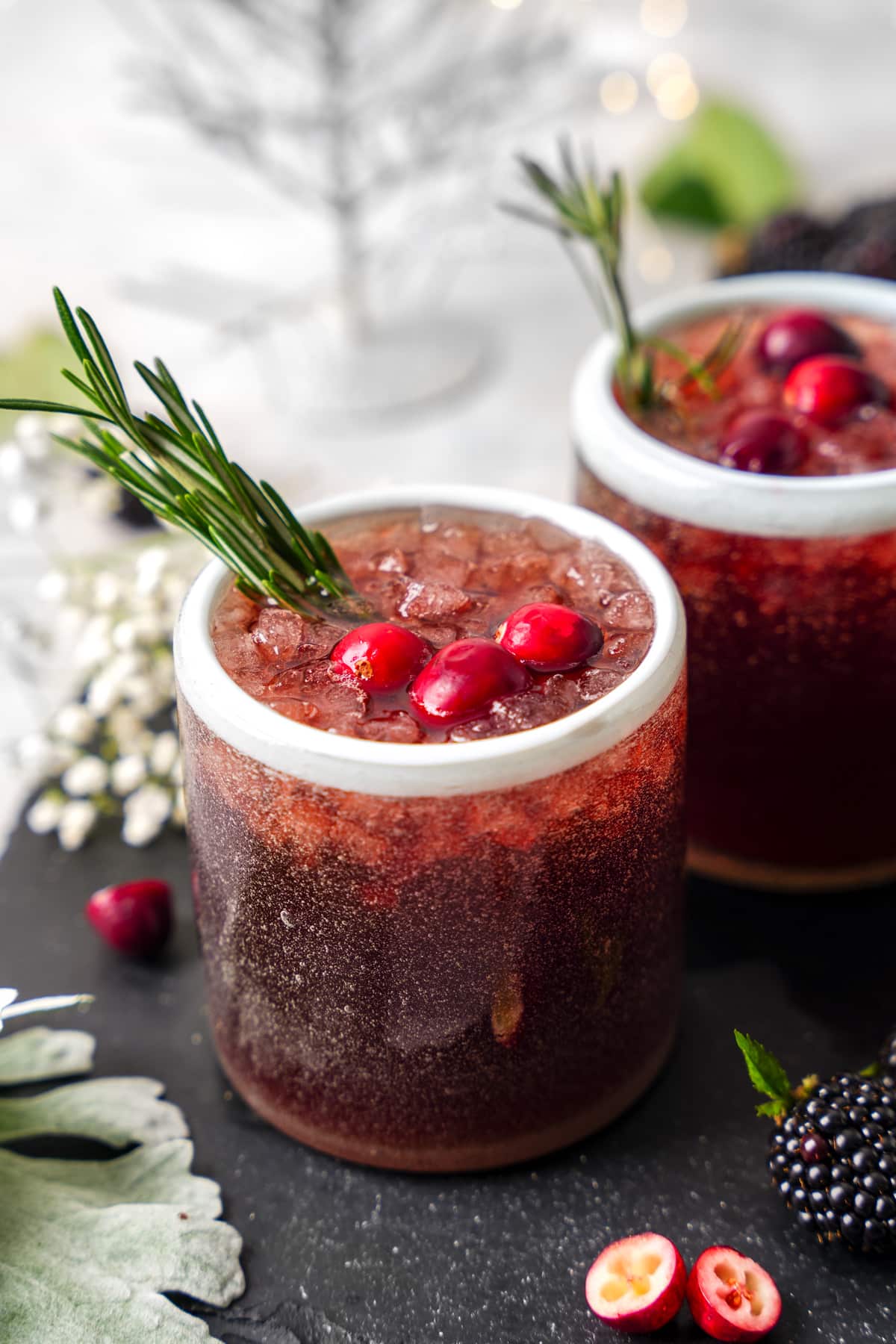 the cranberry mocktail in a glass garnishes with fresh cranberries, and rosemary