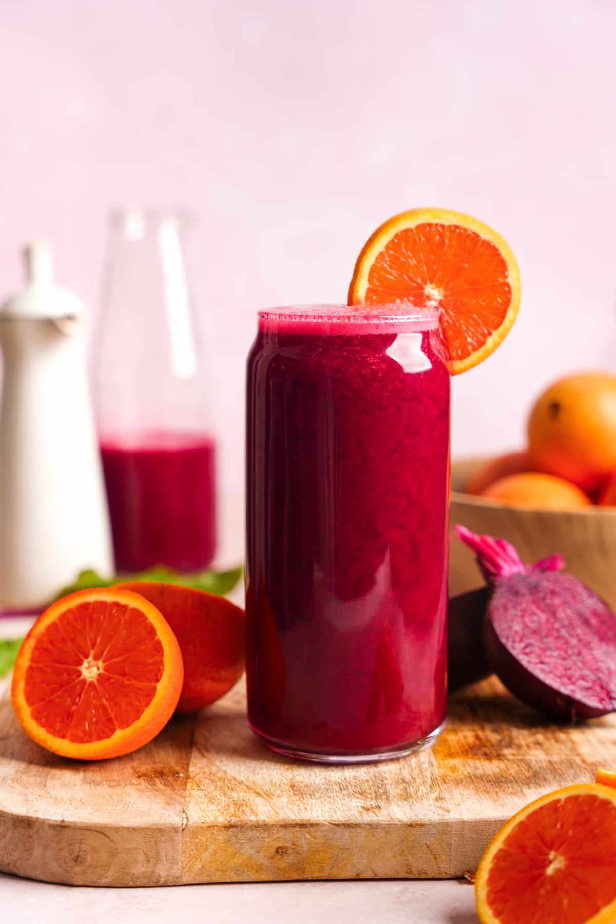 the carrot beet juice in a tall glass with fresh ingredients all around it
