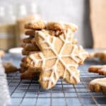 Stack of almond-flour snowflake sugar cookies on a cooling rack, decorated with white vanilla icing in intricate snowflake patterns.