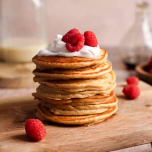 a stack of protein pancakes topped with fresh fruit and coconut yogurt