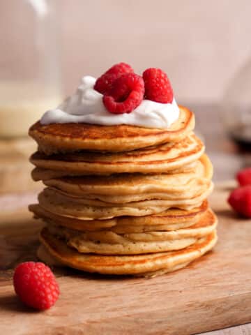 a stack of protein pancakes topped with fresh fruit and coconut yogurt