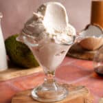 Close-up of creamy vegan soursop ice cream in a glass dessert dish with a smooth texture and tropical ingredients in the background