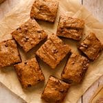 Overhead view of vegan SunButter chocolate chip cookie bars cut into squares and arranged on parchment paper, with golden-brown tops and visible chocolate chips.